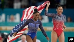 Simone Biles, left, celebrates with teammate Suni Lee, of the U.S., after winning the gold and bronze medals respectively in the women's artistic gymnastics all-around finals in Bercy Arena at the 2024 Summer Olympics in Paris, Aug. 1, 2024.