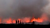 People watch flowing lava during an volcanic eruption near Litli Hrutur, south-west of Reykjavik in Iceland, July 10, 2023.