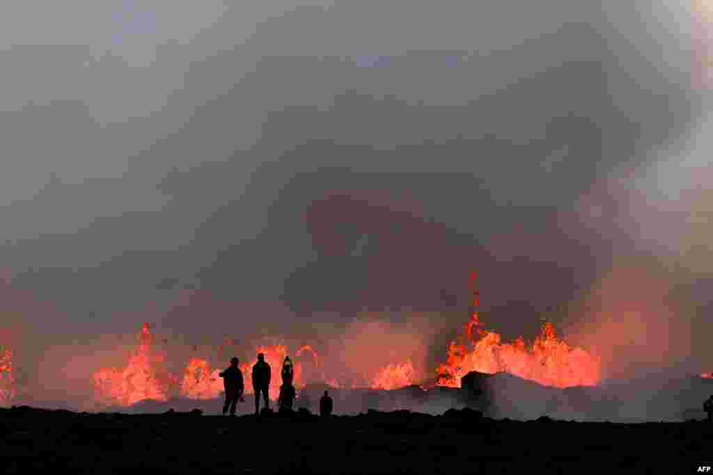 People watch flowing lava during an volcanic eruption near Litli Hrutur, south-west of Reykjavik in Iceland, July 10, 2023.