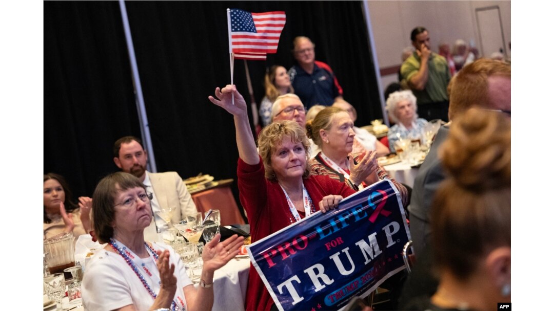 Seorang perempuan yang membawa poster pro-life (kelompok penentang aborsi) mendengarkan pidato mantan presiden AS, Donald Trump, di konvensi Partai Republik di Greensboro, Carolina Utara, Sabtu, 10 Juni 2023. (Foto: Allison Joyce/AFP)