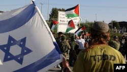 Pasukan keamanan Israel berdiri di antara Pemukim Yahudi dan warga Palestina dalam aksi protes di Qalqiliya, Tepi Barat, pada 9 Mei 2022. (Foto: AFP/Jaafar Ashtiyeh)