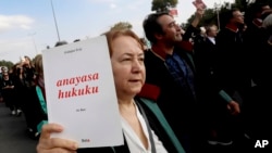 A woman holds a book that reads in Turkish "Constitutional law" during a protest called by the Union of Turkish Bar Associations, in Ankara, Nov. 10, 2023.
