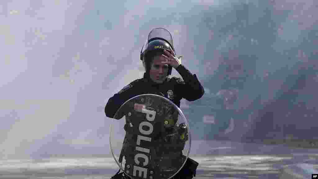 A police officer runs out of a cloud of gas during a demonstration in opposition to a new police training center in Atlanta, Georgia, United States. (AP Photo/Mike Stewart)