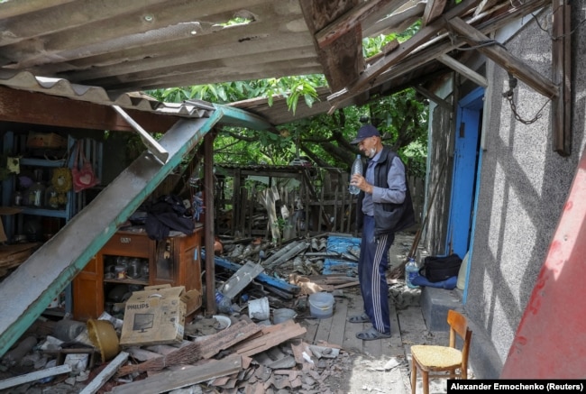 FILE - Local resident Vladimir Odarchenko, 70, stands next to his house damaged during the invasion of the town of Popasna, Ukraine July 14, 2022. (REUTERS/Alexander Ermochenko)