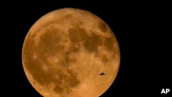 FILE - An airliner flies in front of a supermoon, the first of four this year, on July 3, 2023, in Chicago. August will feature two supermoons.