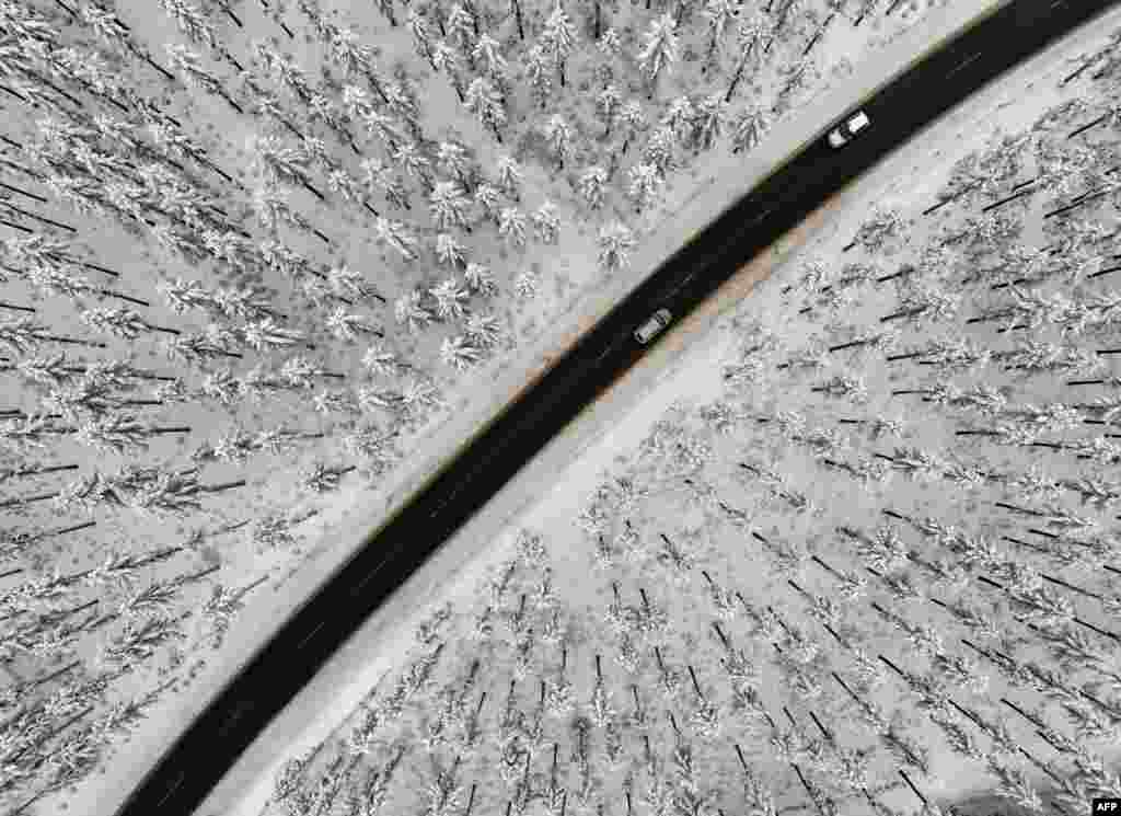 Cars travel on a road in the snow-covered landscape at the Kahler Asten mountain near Winterberg, western Germany.