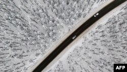 Cars travel on a road in the snow-covered landscape at the Kahler Asten mountain near Winterberg, western Germany. (Photo by Ina FASSBENDER / AFP)