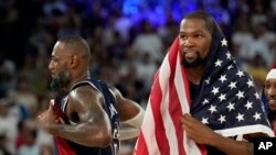 Pebasket AS LeBron James (6) dan Kevin Durrant (7) merayakan kemenangan usai menang medali emas di Bercy Arena, Minggu, 11 Agustus 2024, di Paris, Prancis. (Foto: Mark J. Terrill/AP Photo)