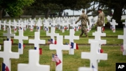 Soldiers walk by headstones in the American Cemetery in Colleville-sur-Mer, Normandy, June 5, 2023.