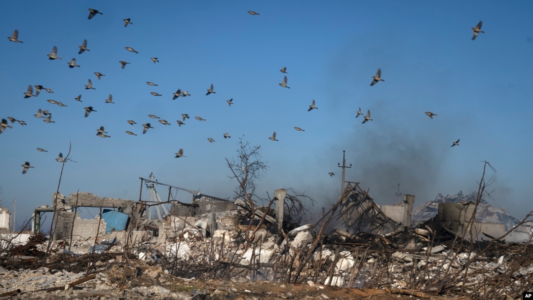 Burung terbang di atas asap yang mengepul dari reruntuhan pertanian pribadi dan lumbung yang masih terbakar setelah serangan roket Rusia baru-baru ini di Desa Kiseliovka dekat Kherson, Ukraina, Jumat, 10 November 2023. (Foto: AP/Efrem Lukatsky)