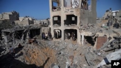 Palestinians look at buildings destroyed in the Israeli bombardment in Deir al Balah, Gaza Strip, Nov. 7, 2023.