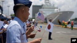 Anggota Penjaga Pantai Filipina mengibarkan bendera kecil Filipina, AS dan Jepang dalam upacara penyambutan kapal penjaga pantai AS dan Jepang di dermaga Manila, Filipina, Kamis, 1 Juni 2023. (AP/Aaron Favila)