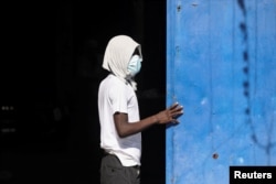 An inmate stands at the gate of the National Penitentiary following violent clashes that led to a prison break, in Port-au-Prince, Haiti, March 3, 2024.