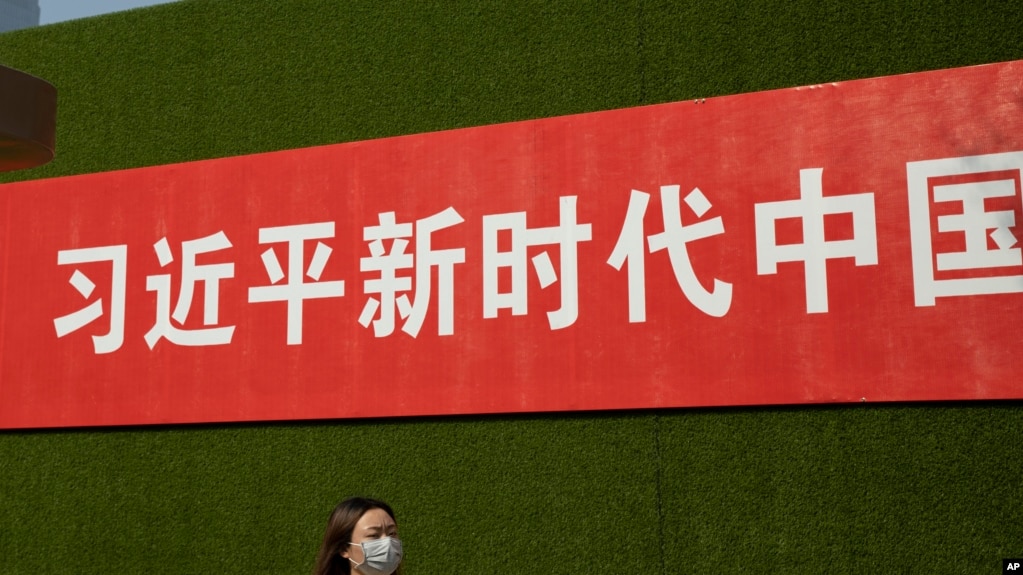 一名女子從北京街頭張貼的一條宣傳習近平新時代的標語下走過。（2019年9月27日）