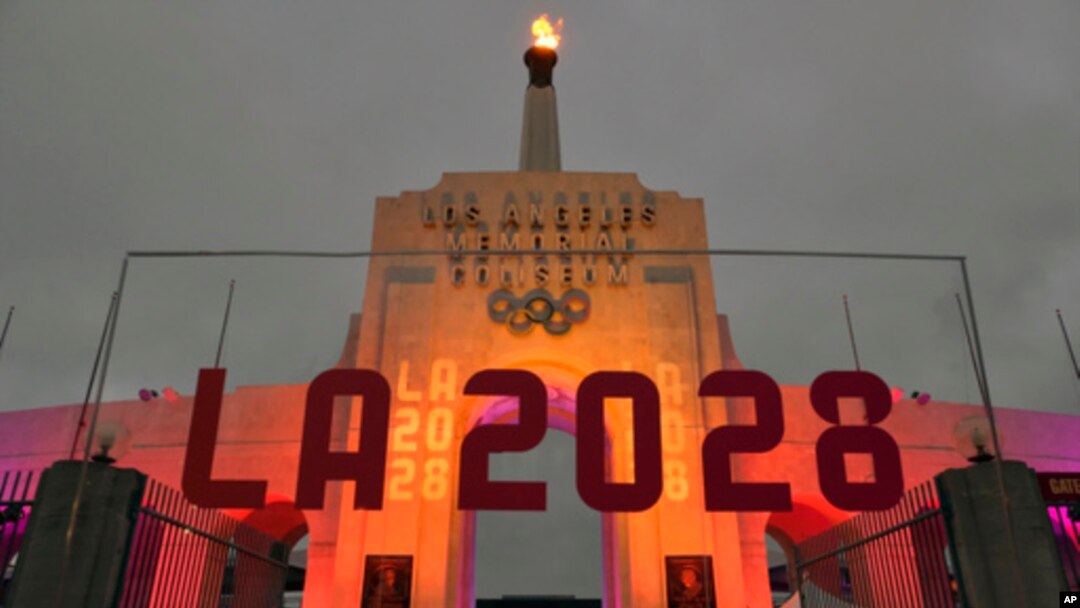 FILE - An LA 2028 sign is seen in front of the Olympic cauldron at the Los Angeles Memorial Coliseum, Sept. 13, 2017. 