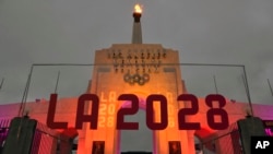 FILE - An LA 2028 sign is seen in front of the Olympic cauldron at the Los Angeles Memorial Coliseum, Sept. 13, 2017.