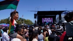 FILE: Julien James carries his son, Maison, 4, holding a Pan-African flag, to celebrate during a Juneteenth commemoration in Los Angeles on June 18, 2022.