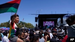 FILE: Julien James carries his son, Maison, 4, holding a Pan-African flag, to celebrate during a Juneteenth commemoration in Los Angeles on June 18, 2022.