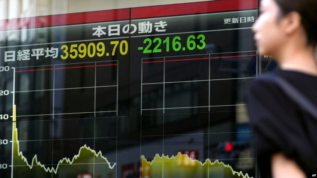 A person walks in front of an electronic stock board showing Japan's Nikkei 225 index, Aug. 2, 2024, in Tokyo. 