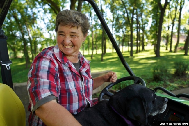 Sister Elaine Fischer rides through the Mount St. Scholastica Benedictine monastery grounds with Sophie, the community's dog, on Wednesday, July 17, 2024, in Atchison, Kansas. (AP Photo/Jessie Wardarski)