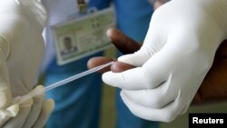 FILE - a counsellor, prepares to get a blood sample from a woman to test for HIV at the Mater Hospital in Kenya's capital Nairobi, September 10, 2015.