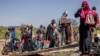 FILE - Sudanese refugees and ethnic South Sudanese who have fled the war in Sudan carry their belongings while boarding a boat at the shores of the White Nile River in the Port of Renk on February 14, 2024.