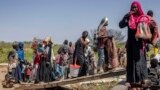 FILE - Sudanese refugees and ethnic South Sudanese who have fled the war in Sudan carry their belongings while boarding a boat at the shores of the White Nile River in the Port of Renk on February 14, 2024.