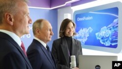 Russian President Vladimir Putin, center, and Sberbank CEO German Gref, left, visit an exhibition on artificial intelligence in Moscow, Russia, Nov. 24, 2023.