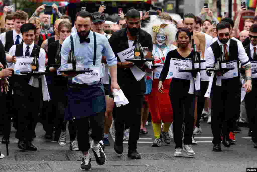 People compete in the waiters race at the Soho Village Fete in London.