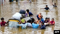 People carry their belongings as they wade through a flooded street after heavy monsoon rains, in Vijayawada, India.