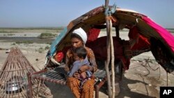 A nomad takes care of her child as they sit in at a hut, in Rajanpur, a district of Pakistan's Punjab province, May 21, 2023.