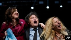 资料照片：2023年10月18日，在阿根廷布宜诺斯艾利斯举行的竞选集会上，总统候选人哈维尔·米莱（中）、他的妹妹卡琳娜（右）和他的竞选搭档维多利亚·比利亚鲁尔拥抱。（美联社照片）