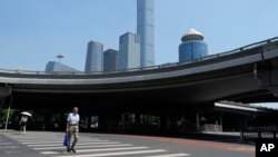 A man crosses the road near the central business district in Beijing, July 17, 2023. China's economy grew at a 6.3% annual pace in the April-June quarter, much lower than analysts had forecast given the slow pace of growth the year before. 