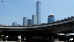 FILE - A man crosses the road near the central business district in Beijing, July 17, 2023. Yan Bingzhu, the former chairman of the state-owned Bank of Beijing is under investigation for corruption, March 3, 2024. 