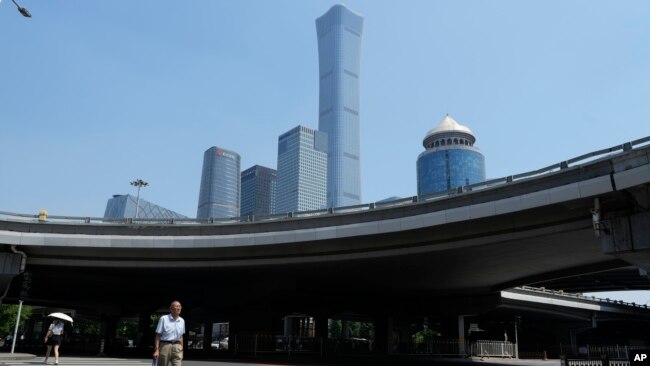 FILE - A man crosses the road near the central business district in Beijing, July 17, 2023. Yan Bingzhu, the former chairman of the state-owned Bank of Beijing is under investigation for corruption, March 3, 2024.