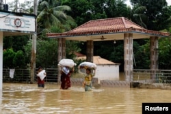 FILE - People wade through floodwaters during severe floods in Fazilpur area in Feni, Bangladesh, August 26, 2024.