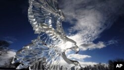 De zon schijnt door een ijssculptuur van een adelaar die is uitgehouwen tijdens het Hunter Ice Festival van dit jaar in het centrum van Niles, Michigan op 19 januari 2024.