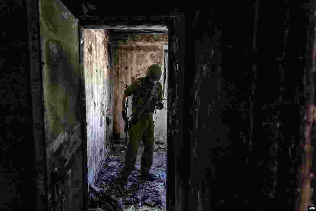 An Israeli soldier stands inside a house burned down during the October 7 attack in Kibbutz Kfar Aza, close to the southern Israeli border with the Gaza Strip.