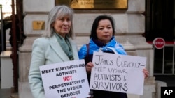 FILE - Helena Kennedy, left, and Rahima Mahmut hold placards as activists protest at the British Foreign Office in London, Feb. 13, 2023. They were demanding a meeting with the foreign secretary to highlight concerns for compatriots in China's Xinjiang Uyghur Autonomous Region.