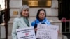 2023年2月13日，人權活動人士海倫娜·肯尼迪（Helena Kennedy）（左）和拉希瑪·馬赫穆特 （Rahima Mahmut） 舉著標語牌在倫敦英國外交部外面抗議。