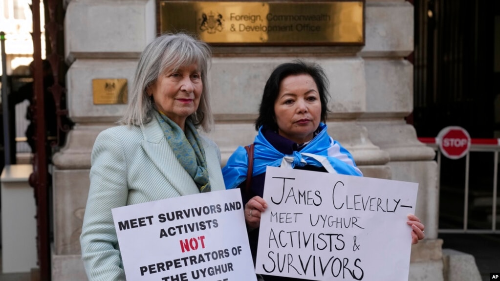 资料照片：人权活动人士海伦娜·肯尼迪（Helena Kennedy）（左）和拉希玛·马赫穆特 （Rahima Mahmut） 举着标语牌在伦敦英国外交部外面抗议,要求英国外相会晤维吾尔活动人士和幸存则。(2023年2月13日，)(photo:VOA)