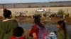 FILE - Migrants seeking asylum in the United States gather on the banks of the Rio Bravo River, as the Texas National Guard waits at the border between the United States and Mexico, as seen from Ciudad Juarez, Mexico, Dec. 5, 2023. 