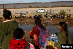 Migrants seeking asylum in the United States gather on the banks of the Rio Bravo river, as the Texas National Guard blocks the crossing at the border between the United States and Mexico, as seen from Ciudad Juarez, Mexico, Dec. 5, 2023.
