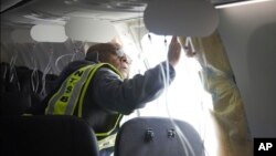 Investigator-in-Charge John Lovell examines the fuselage plug area of Alaska Airlines Flight 1282 on Sunday, Jan. 7, 2024, in Portland, Oregon. (National Transportation Safety Board via AP)