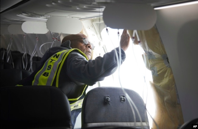 FILE - Investigator-in-Charge John Lovell examines the fuselage plug area of Alaska Airlines Flight 1282 on Sunday, Jan. 7, 2024, in Portland, Oregon. (National Transportation Safety Board via AP)