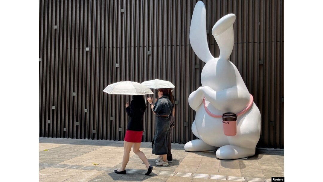Pejalan kaki memegang payung saat berjalan di luar pusat perbelanjaan di tengah peringatan kuning gelombang panas di Shenzhen, Guangdong, China, 2 Juni 2023. (Foto: REUTERS/David Kirton)