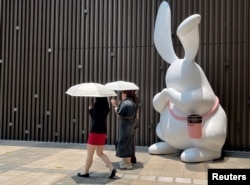 Pejalan kaki memegang payung saat berjalan di luar pusat perbelanjaan di tengah peringatan kuning gelombang panas di Shenzhen, Guangdong, China, 2 Juni 2023. (Foto: REUTERS/David Kirton)