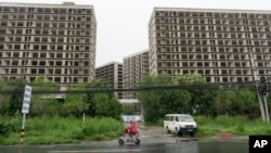 FILE - A rider passes by an abandoned construction project on the outskirts of Beijing, July 25, 2024. 