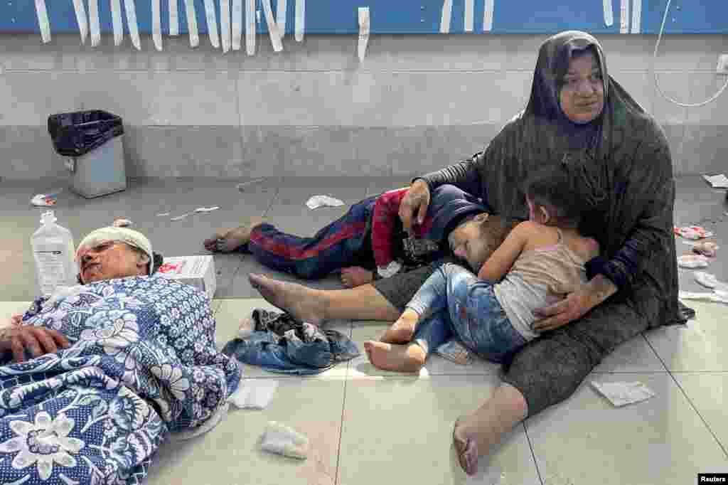 An injured Palestinian woman holds her children, who were wounded in an Israeli strike, at Shifa hospital in Gaza City.