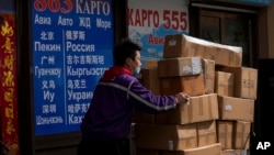 Seorang pekerja kurir memindahkan barang di pusat perdagangan yang juga dikenal sebagai Pasar Rusia di Beijing, Minggu, 27 Februari 2022. (Foto: AP)